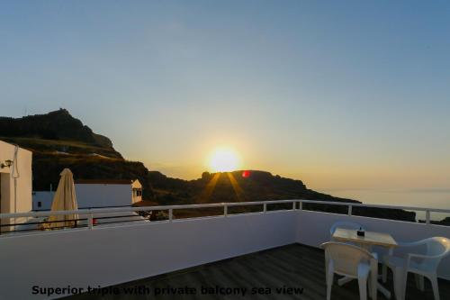 a view of the sunset from a balcony with a table and chairs at St. Paul's Bay View Suites in Líndos