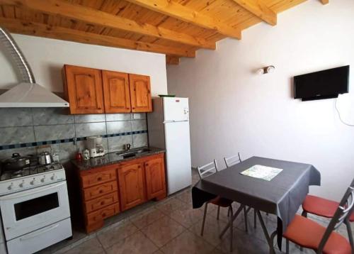 uma cozinha com uma mesa e um frigorífico branco em Alquileres Oeste 1 em Puerto Madryn