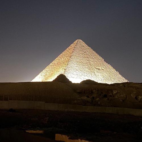 a pyramid in the distance with the sun behind it at Pyramids Lounge Guest House in Cairo