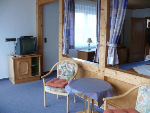 Hemfurth-Edersee的住宿－多恩羅森索瓦爾德霍特爾酒店，一间设有两把椅子、一张桌子和一台电视的房间