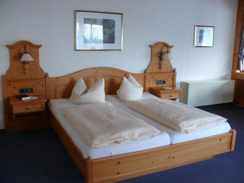 a bedroom with a wooden bed with white sheets and pillows at Waldhotel Dornröschenshöh in Hemfurth-Edersee