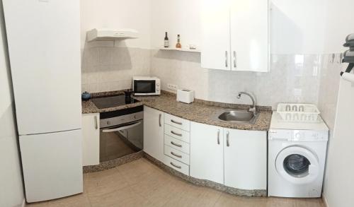 uma cozinha branca com uma máquina de lavar roupa e um micro-ondas em Casa Analiz em Arrecife