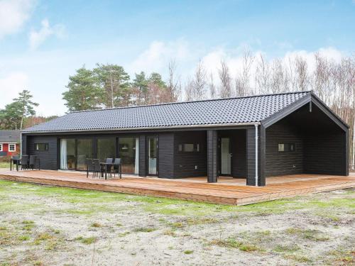 a black house with a wooden deck in a field at 8 person holiday home in Læsø-By Traum in Læsø