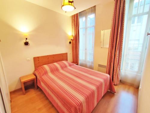 Dormitorio pequeño con cama con manta a rayas en L'Eterlou, T3, centre Luchon, wifi, casier à skis, 6 personnes en Luchon