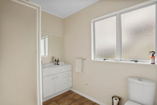 a bathroom with a toilet and a sink and a window at Gorgeous 2BR Central Akl Retreat - WI-FI - Netflix in Auckland