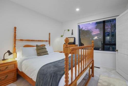 a bedroom with a wooden bed and a window at Countryside Calm Getaway with pool and deck in Auckland