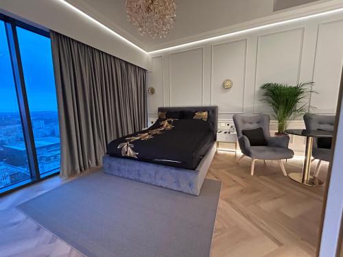 a bedroom with a bed and a table and a chair at Hanza Tower HOME4U in Szczecin