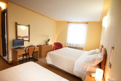 a hotel room with two beds and a television at Hotel San Marco in Bedonia