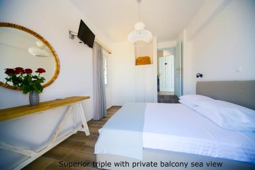 a bedroom with a large white bed and a mirror at St. Paul's Bay View Suites in Líndos