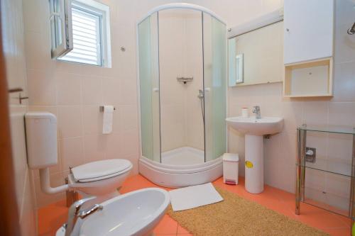 een badkamer met een douche, een toilet en een wastafel bij Apartman Nikodem in Novalja