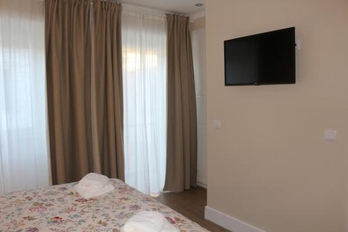 a bedroom with a bed and a television on a wall at Cerveira House in Vila Nova de Cerveira