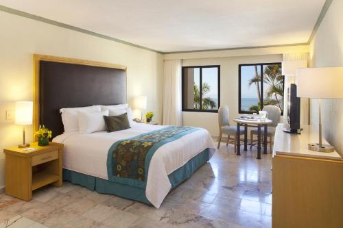 a hotel room with a bed and a table and chairs at Samba Vallarta All Inclusive in Nuevo Vallarta 