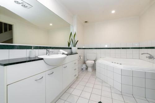 a white bathroom with a sink and a tub and a toilet at Brunswick 3bdrm townhouse, with parking by Custom Bnb Hosting in Melbourne