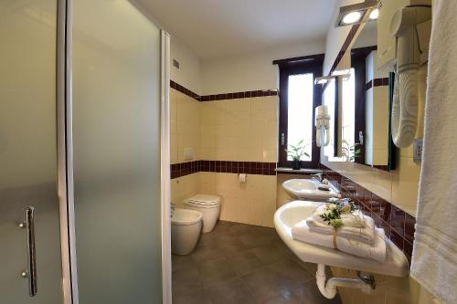 bagno con 2 lavandini e servizi igienici di Hotel Rioverde a Pralormo
