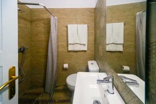 a bathroom with a sink and a toilet and a mirror at St. Paul's Bay View Suites in Líndos