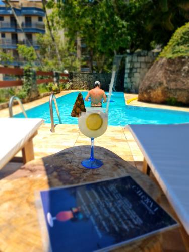 a man sitting in a chair in front of a swimming pool at Apartamentos Casa da Pedra in Ubatuba