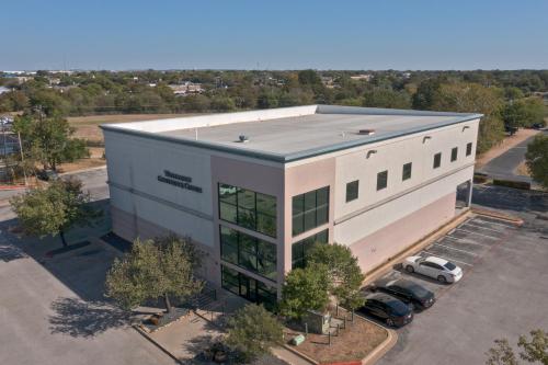 an overhead view of a building with cars parked outside at Wingate by Wyndham and Williamson Conference Center in Round Rock