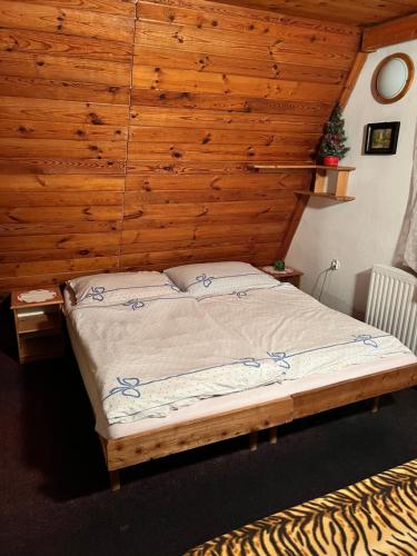 a bed in a room with a wooden wall at Chata Tatranka in Štôla