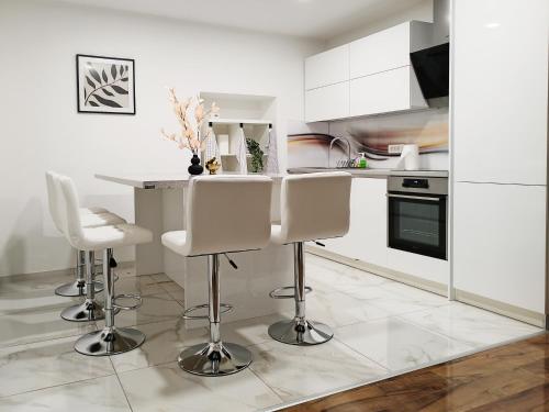 a white kitchen with white cabinets and white stools at Stara Pošta Apartment 8 in Grosuplje