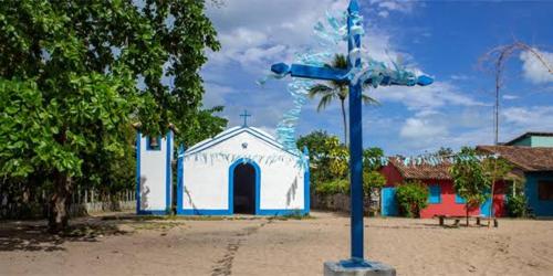 una cruz azul delante de una pequeña iglesia en Casa da Lua no centro da Vila de Caraíva ao lado da Igreja de Caraíva, en Caraíva