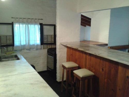 cocina con encimera y taburetes en una habitación en Alquilo Casa en Tanti in 