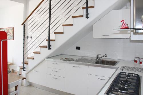 una cocina con armarios blancos y una escalera en Grillo Casa Vacanze en Tessera