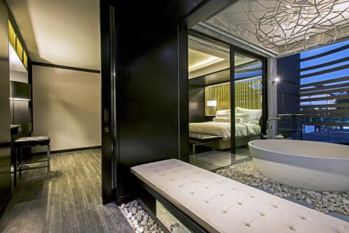 a bathroom with a large tub and a bedroom at AMANOR Hotel Chiang Mai in Chiang Mai