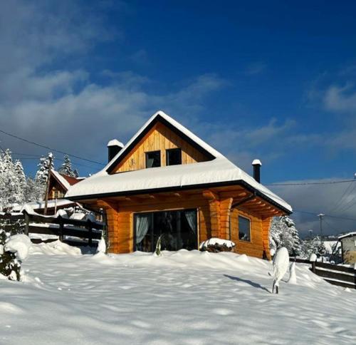 a log cabin in the snow with a sheep standing in front at MamChwilkeHome in Istebna