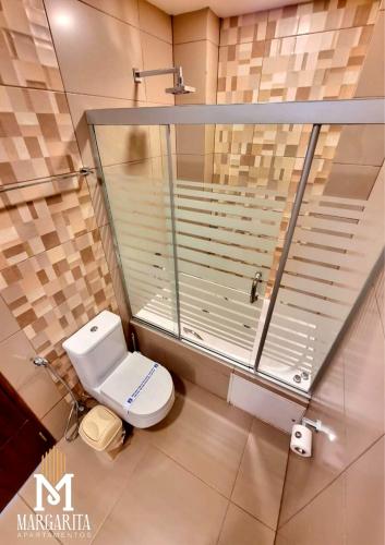a bathroom with a toilet and a glass shower at Margarita Apartamentos in Cochabamba