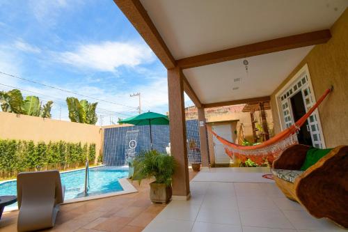 un patio con una hamaca y una piscina en Casa de Praia Pouso das Fadas com Arrumadeira e Equipe de Cozinha en Maragogi