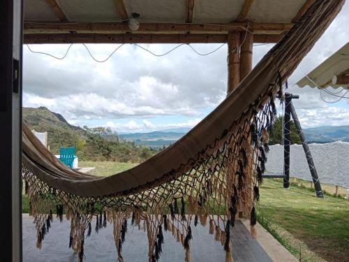 uma rede de descanso com vista para a água e as montanhas em Cabañas camino al cielo em Fúquene