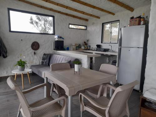 una cucina e un soggiorno con tavolo e frigorifero di Cabañas camino al cielo a Fúquene