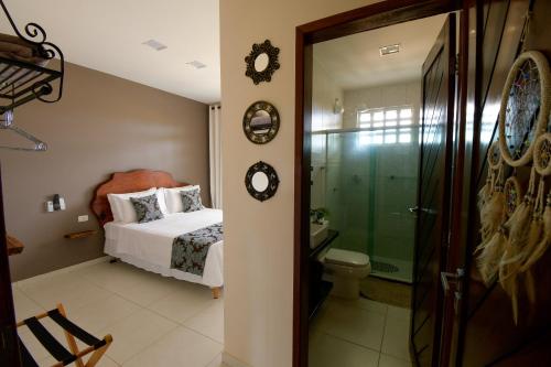 a bedroom with a bed and a bathroom with a shower at Casa Pouso das Fadas com Arrumadeira e Cozinheira Profissional in Maragogi
