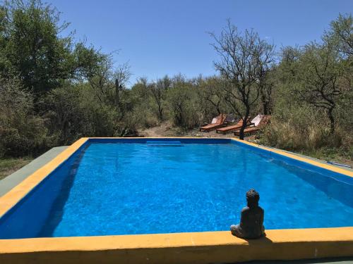 une personne assise à côté d'une piscine bleue dans l'établissement Cabañas Taos Pueblo, à Capilla del Monte