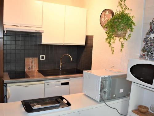 une cuisine avec des placards blancs et un four micro-ondes sur un comptoir dans l'établissement Charmant 2 pièces près des pistes avec balcon et piscine chauffée - FR-1-464-9, à Pralognan-la-Vanoise
