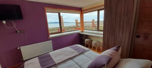 Schlafzimmer mit lila Wänden, einem Bett und einem Balkon in der Unterkunft Hotel CasaQuinchao in Achao