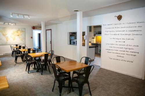 a restaurant with tables and chairs and a wall with writing on it at Auberge Manitonga in Mont-Tremblant