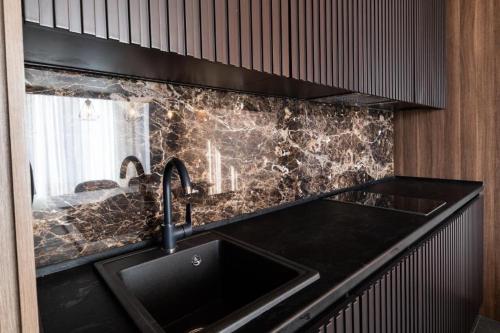 uma cozinha com um lavatório e uma bancada preta em Woodside apartments Kopaonik em Kopaonik