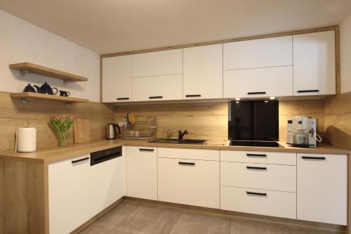 a kitchen with white cabinets and a black appliance at Willa na Plażowej in Węgierska Górka