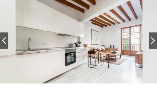 una cucina con mobili bianchi, tavolo e sedie di Hotel-Apartment Modern Studio a Palma de Mallorca