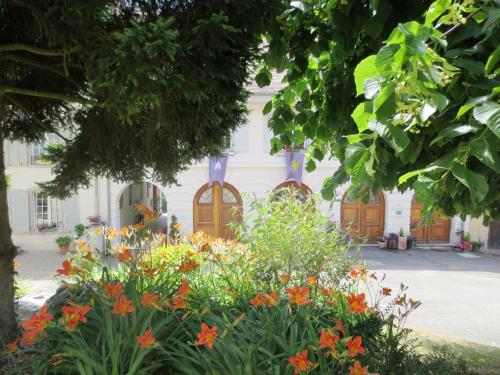 a garden with flowers in front of a white building at La Maison des Fontaines d'Alsace in Ferrette