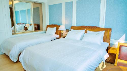 two beds in a bedroom with blue walls at Fontana Beach Hotel in Mokpo