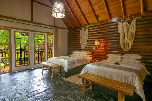 two beds in a room with wooden walls and windows at Santa María Resort in Santa María del Oro