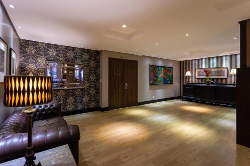 a living room with a leather couch and wooden floors at Faial Prime Suítes in Florianópolis