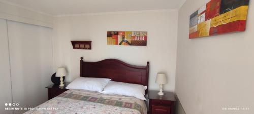 a bedroom with a bed with two night stands and two lamps at Departamento Full 3D 2B Cerca de Playas en Arica in Arica