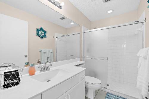 a white bathroom with a sink and a toilet at Serene Seaside Retreat - Dog friendly - 2BR Townhouse with Heated Pool Steps to Paradise Beach! in Melbourne