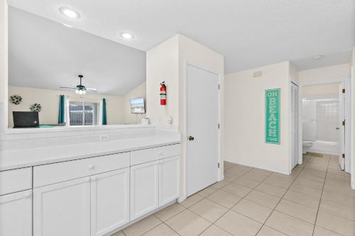 a white bathroom with a sink and a mirror at Oceanview Haven - 2BR Beach House with Patio Heated Pool Steps from Paradise Beach Park! in Melbourne