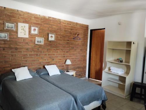 een slaapkamer met 2 bedden en een bakstenen muur bij El Poblador in Santa Rosa