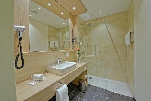 a bathroom with a sink and a shower at H+ Hotel Stade Herzog Widukind in Stade