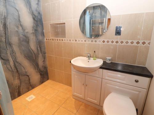 a bathroom with a sink and a toilet and a mirror at Sonya's Cottage in Anthorn